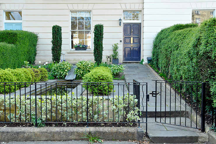 Picture of a white house with a black gate in front garden