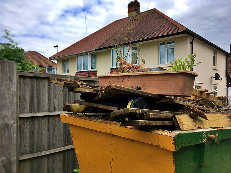 Picture of a rubbish skip with old fencing panels in it 