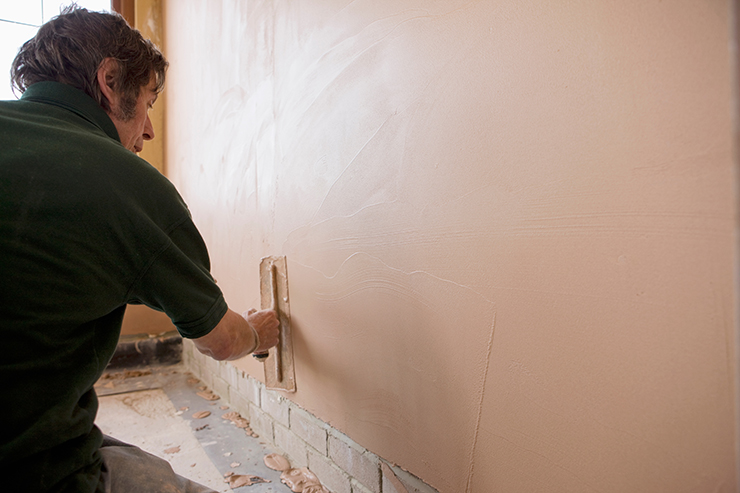 Picture pf a tradesperson adding a layer of plaster to the wall