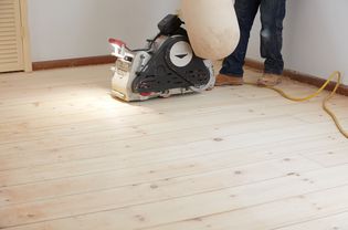 Sander machine with cord passing next to person standing on hardwood floor