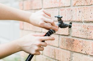 person checking an outdoor spigot