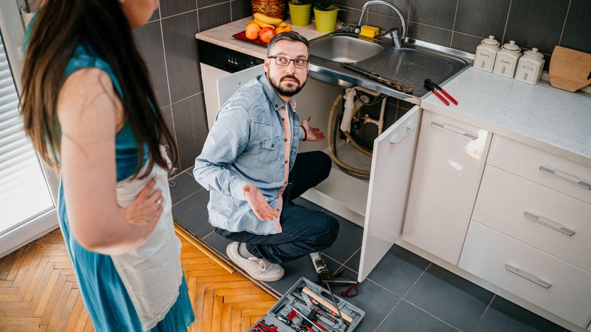 A man fixing the sink's clogged drains.