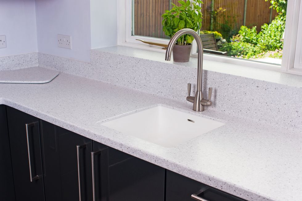 state of the art domestic kitchen with hi gloss grey cupboards and oak cabinets and induction hob, set in a stone resin worktop