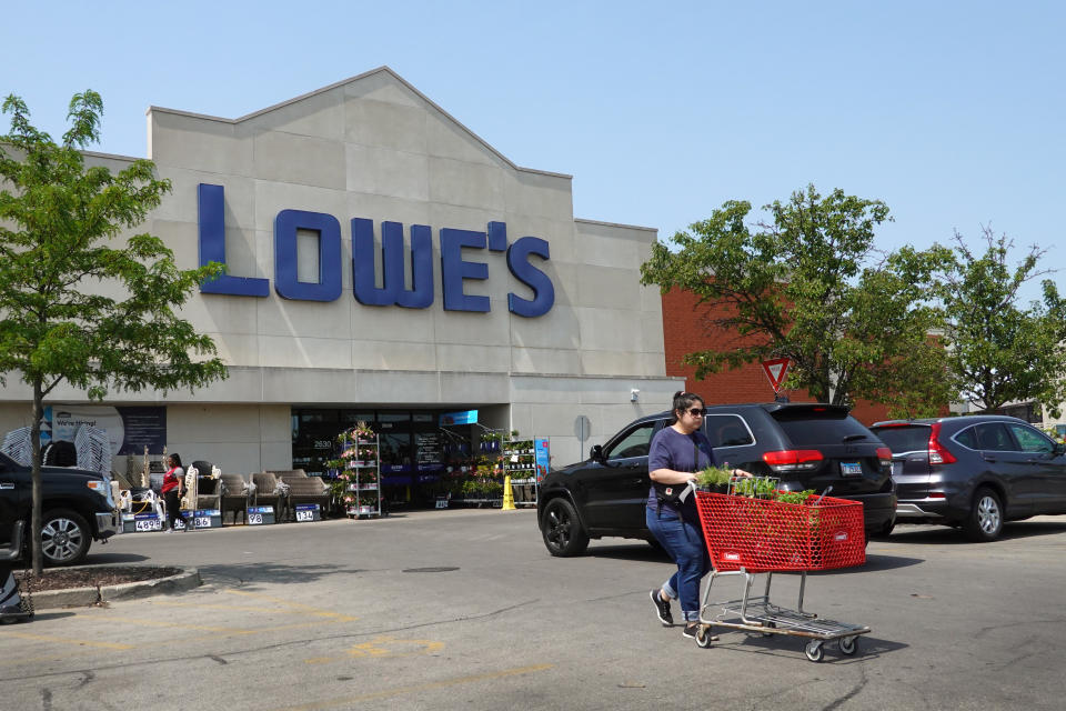 A customers pushes a cart full of plants outside a Lowe's store.