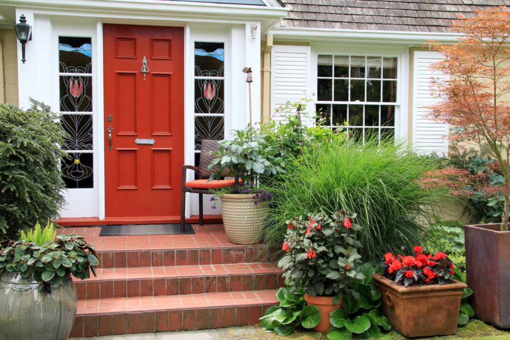 Front door painted in red with plants on steps 