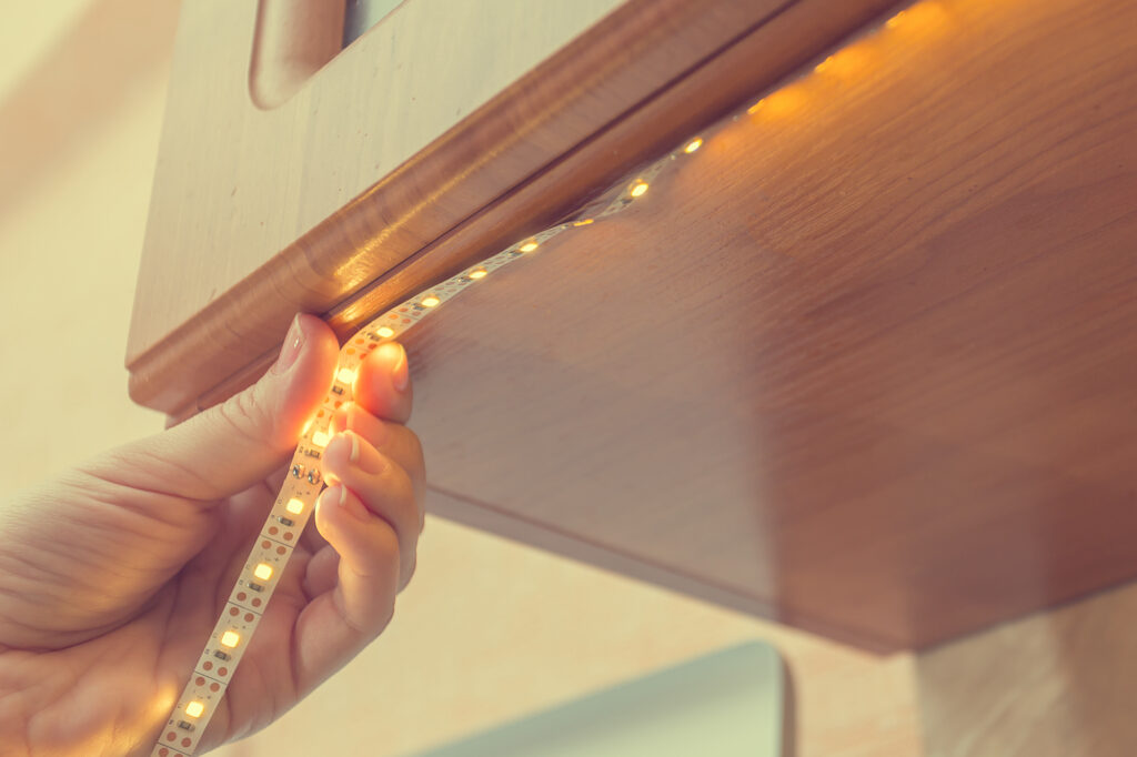 Picture of a hand installing LED light strips below cabinet 